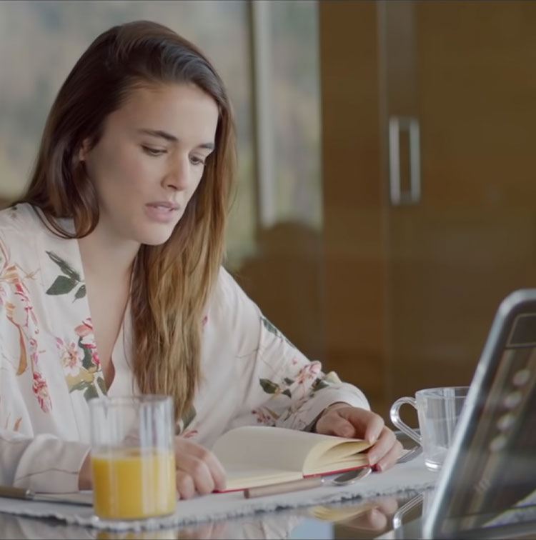 Beyond Money short film screenshot: Woman reading book in front of computer screen