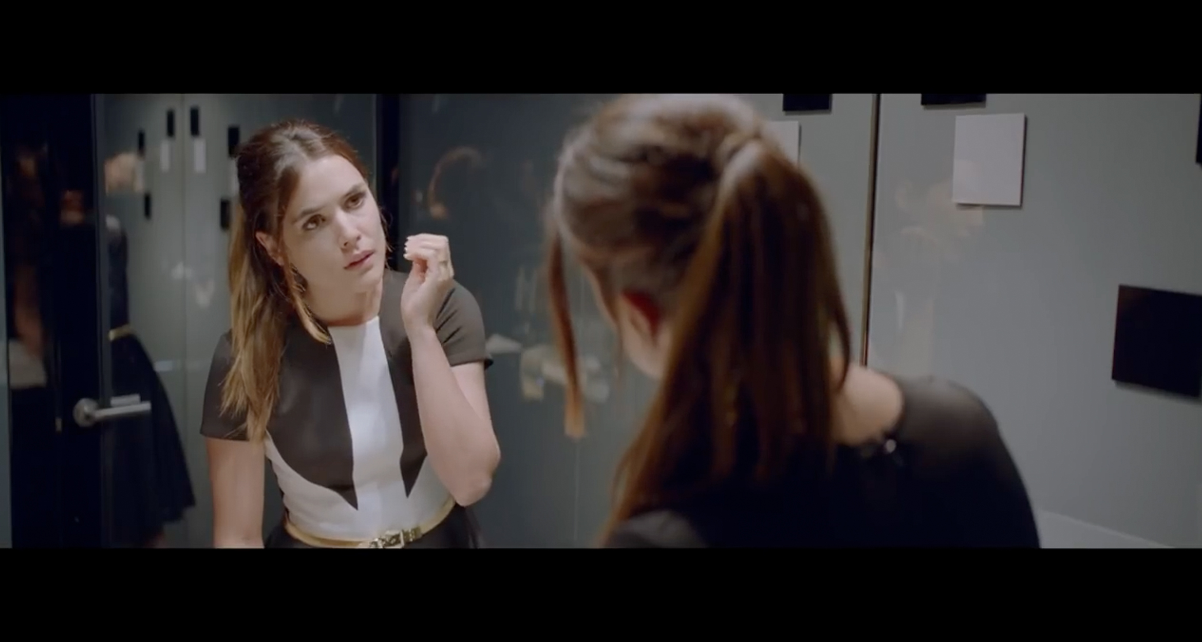 Screenshot from Beyond Money short film: Woman looking at her reflection in a mirror. 