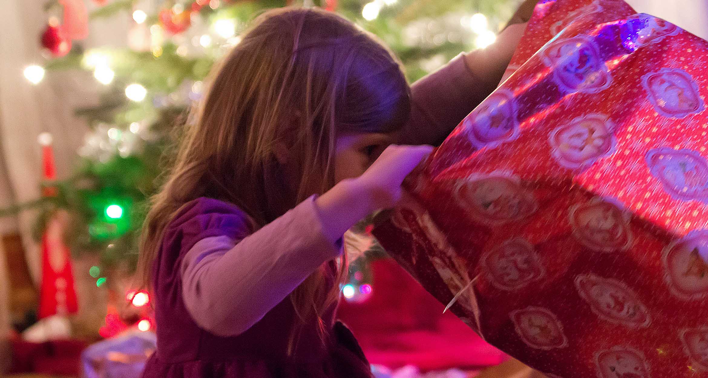 Young girl looking into holiday gift-wrapped box 