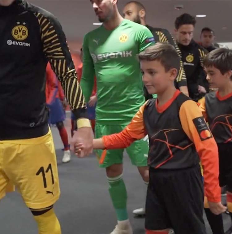 Children wearing Kit Beats jerseys holding hands with football players 