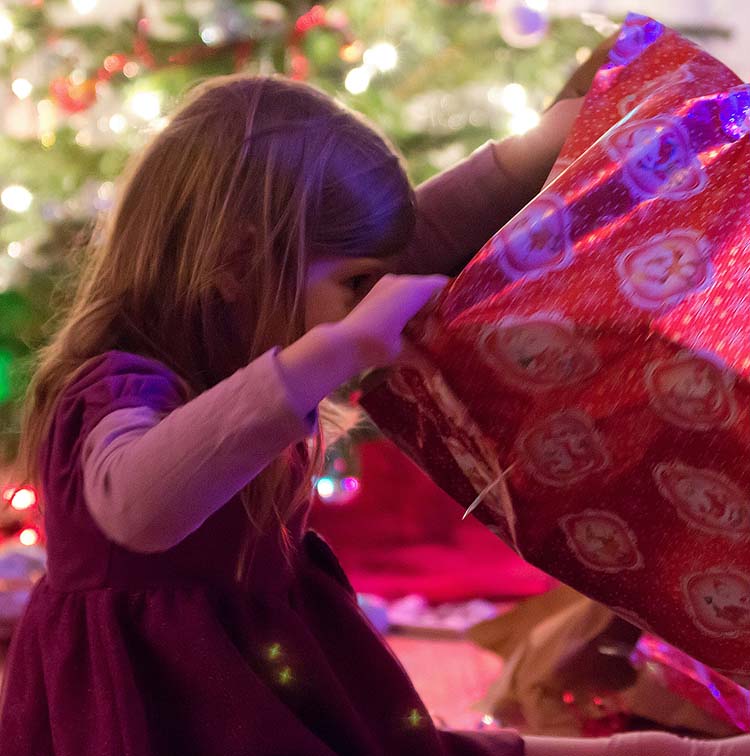 Young girl looking into holiday gift-wrapped box 